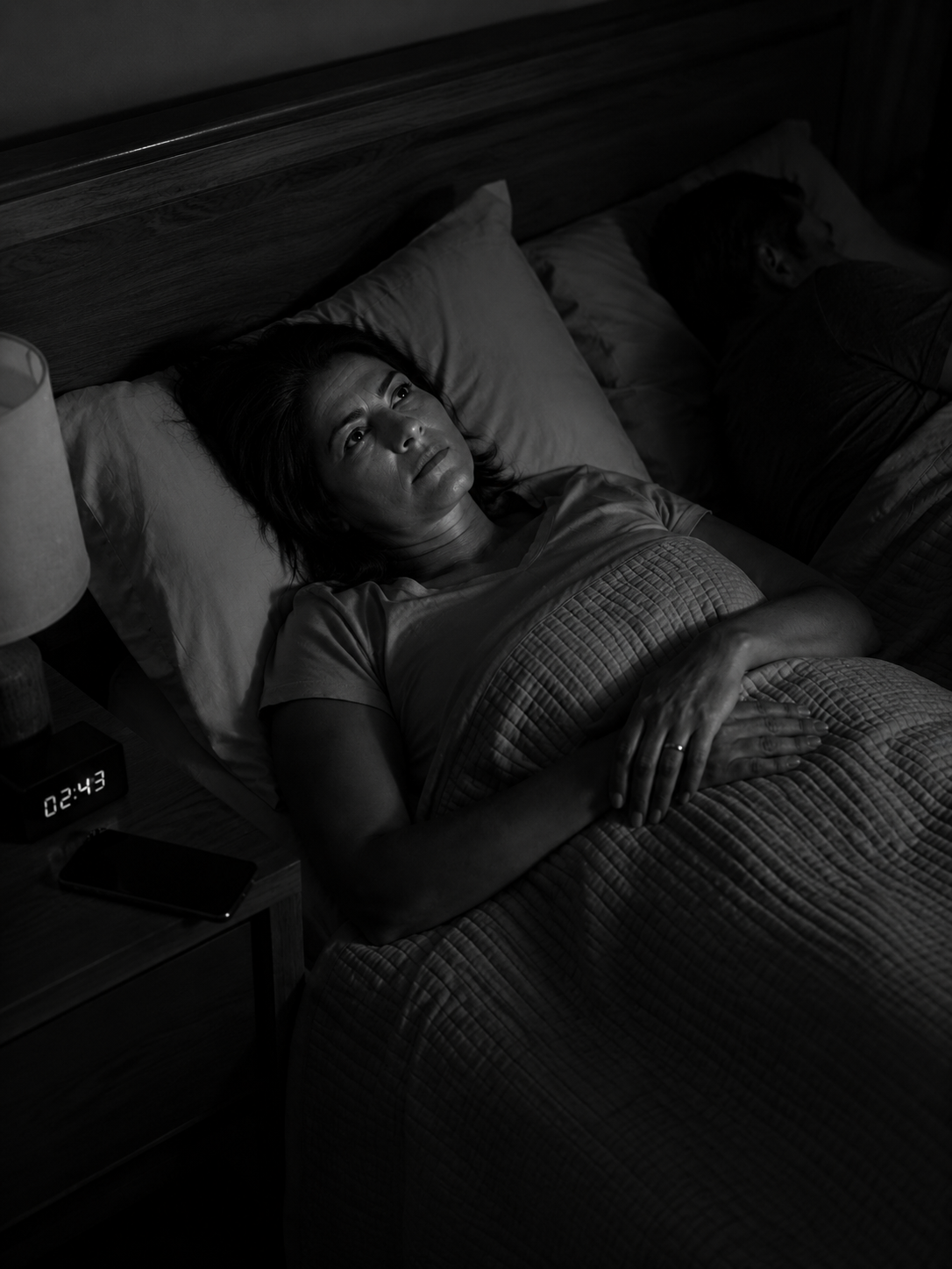 Mulher acordada na cama, olhando para o teto à noite